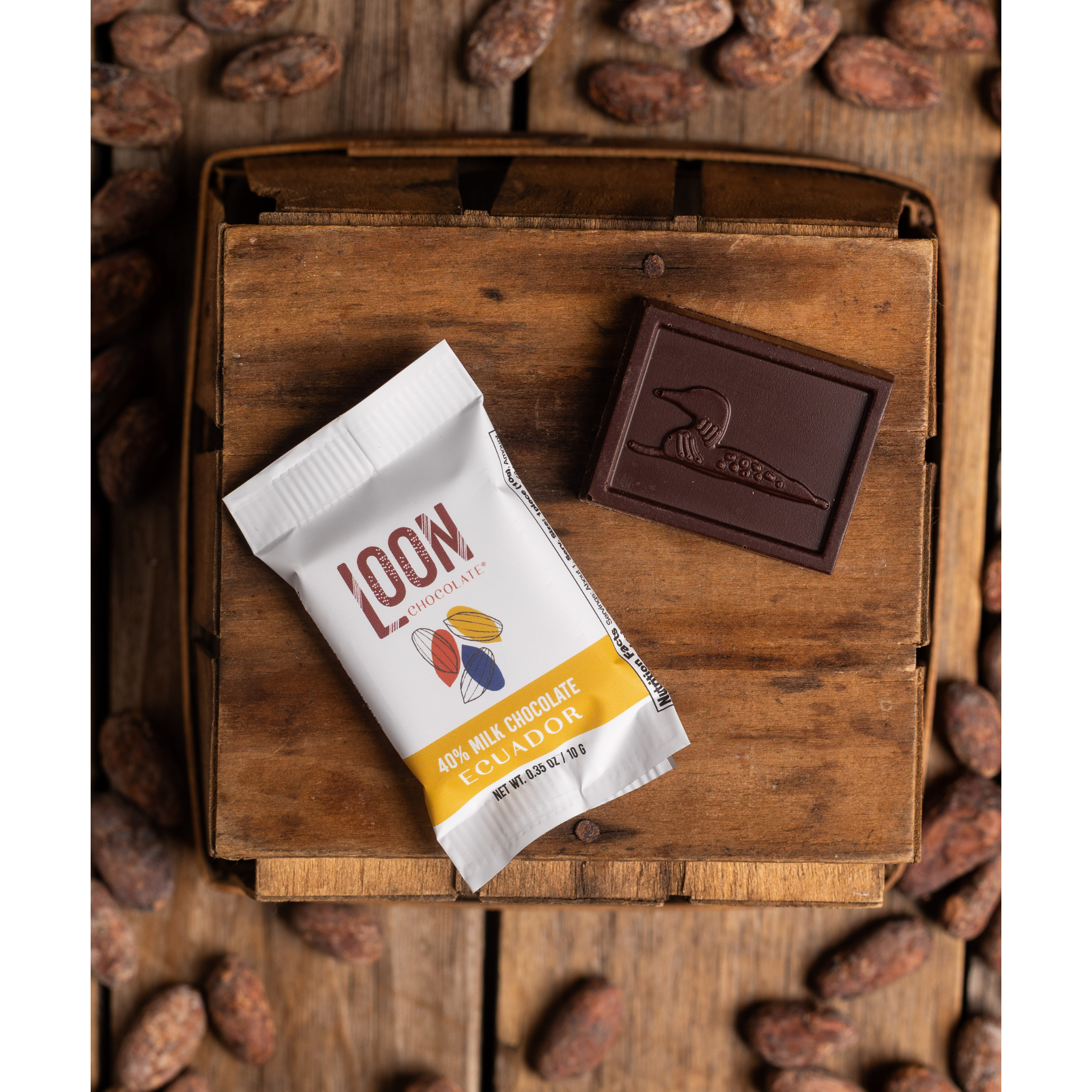 40% Ecuador Milk Chocolate Mini Bar by Loon Chocolate on wooden surface with cacao beans