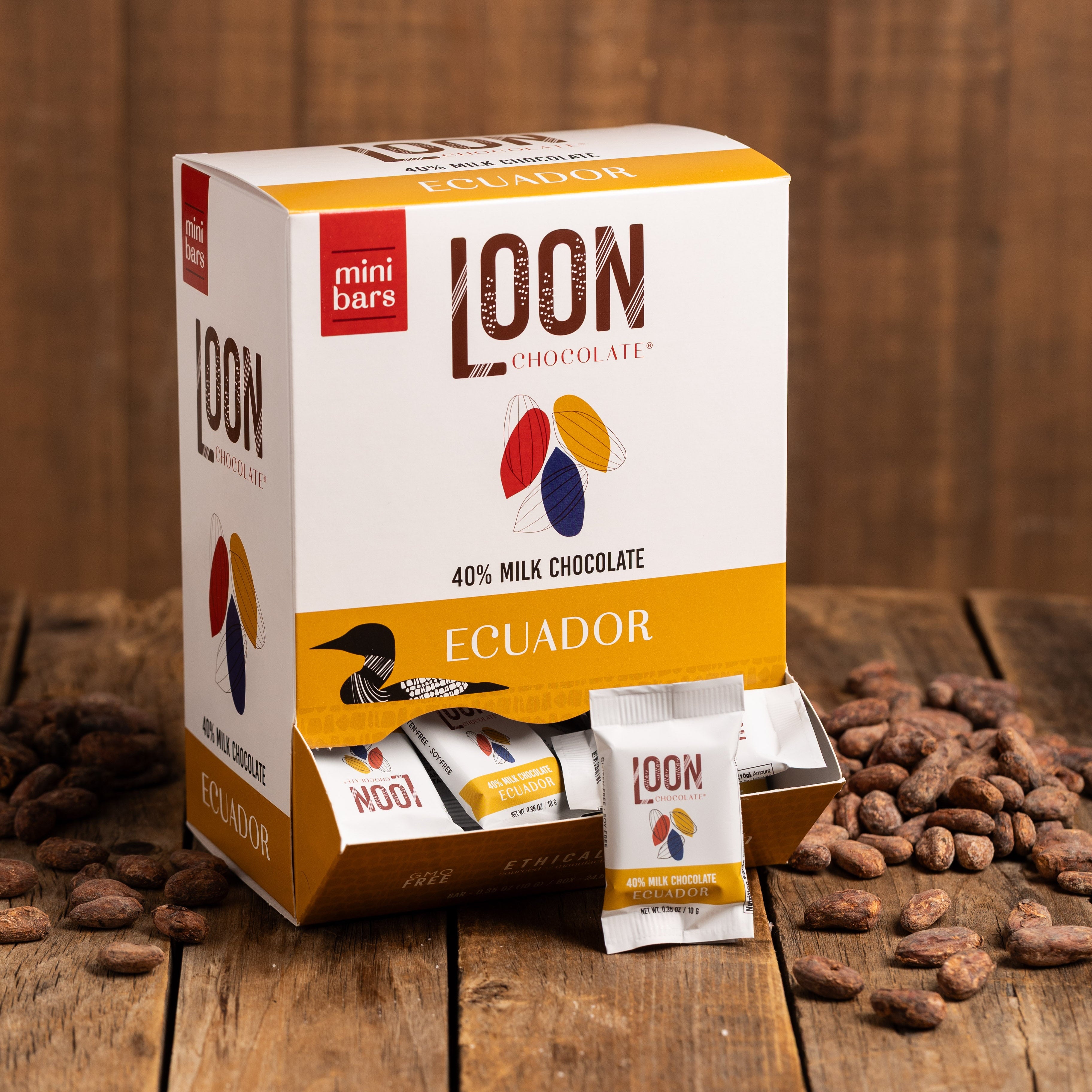 Box of 40% Ecuador Milk Chocolate mini bars by Loon Chocolate on wooden surface with cacao beans